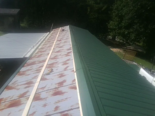 Old rusted panels beside newly installed green metal roofing — Wind Damage Roof Repair by Roofing Brothers in Melba