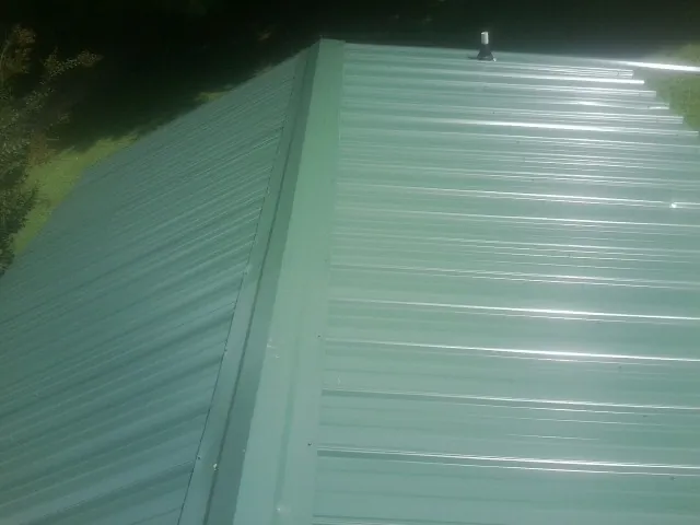 New green metal panels meeting at the ridge of a roof — Flat Roof Repair work by our crew in Melba