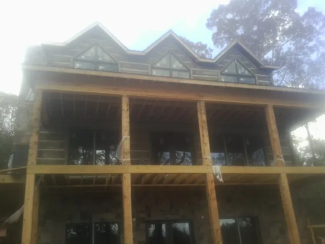 Dormers and porch framing on a large log home under construction — Roof Coating work by our crew in Melba