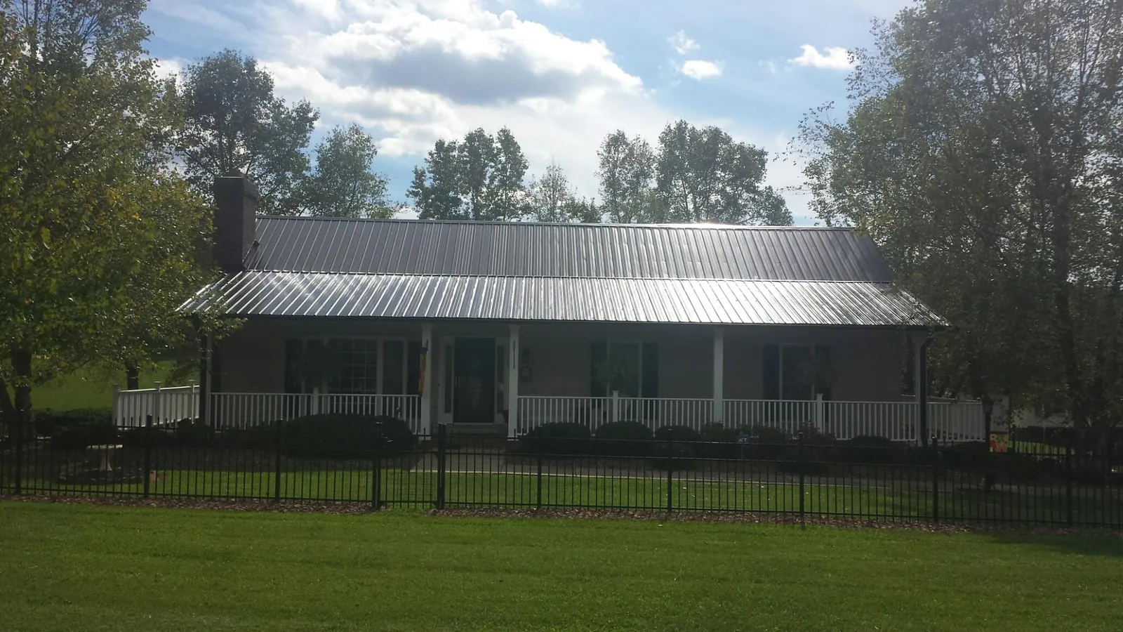Gray metal roof on a brick ranch with a full width front porch — Gutter Guard Installation work by our crew in Melba
